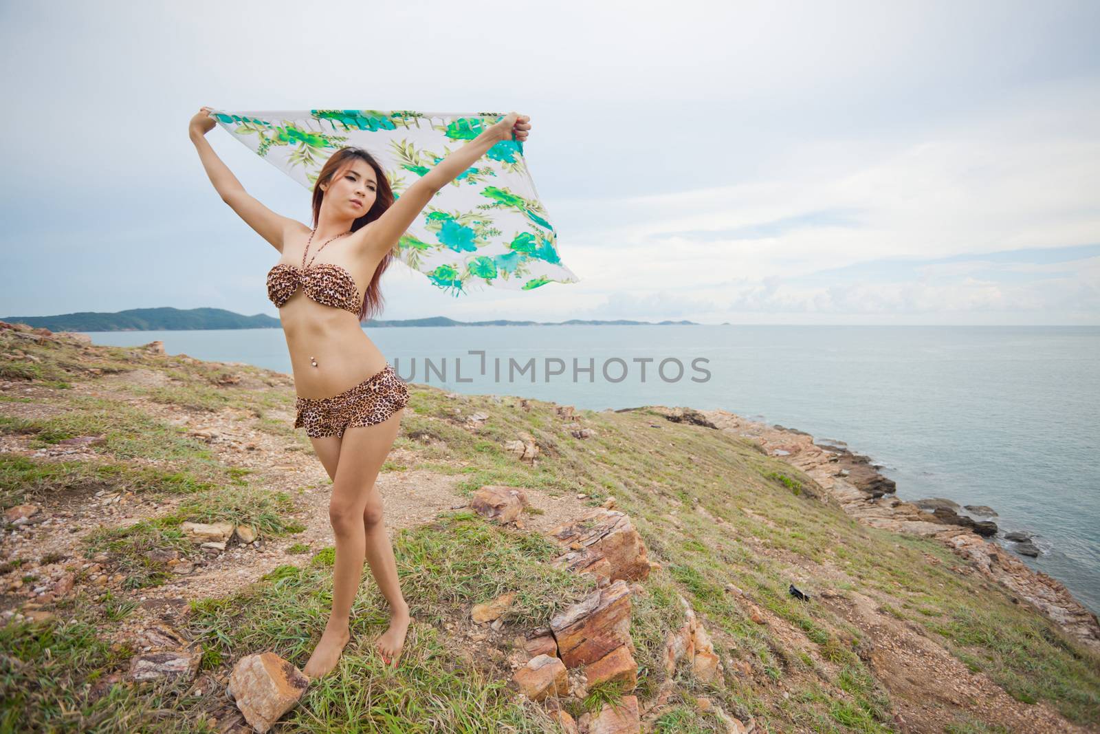 Portrait of sexy young asian woman with blowing fabric on mountain and sea