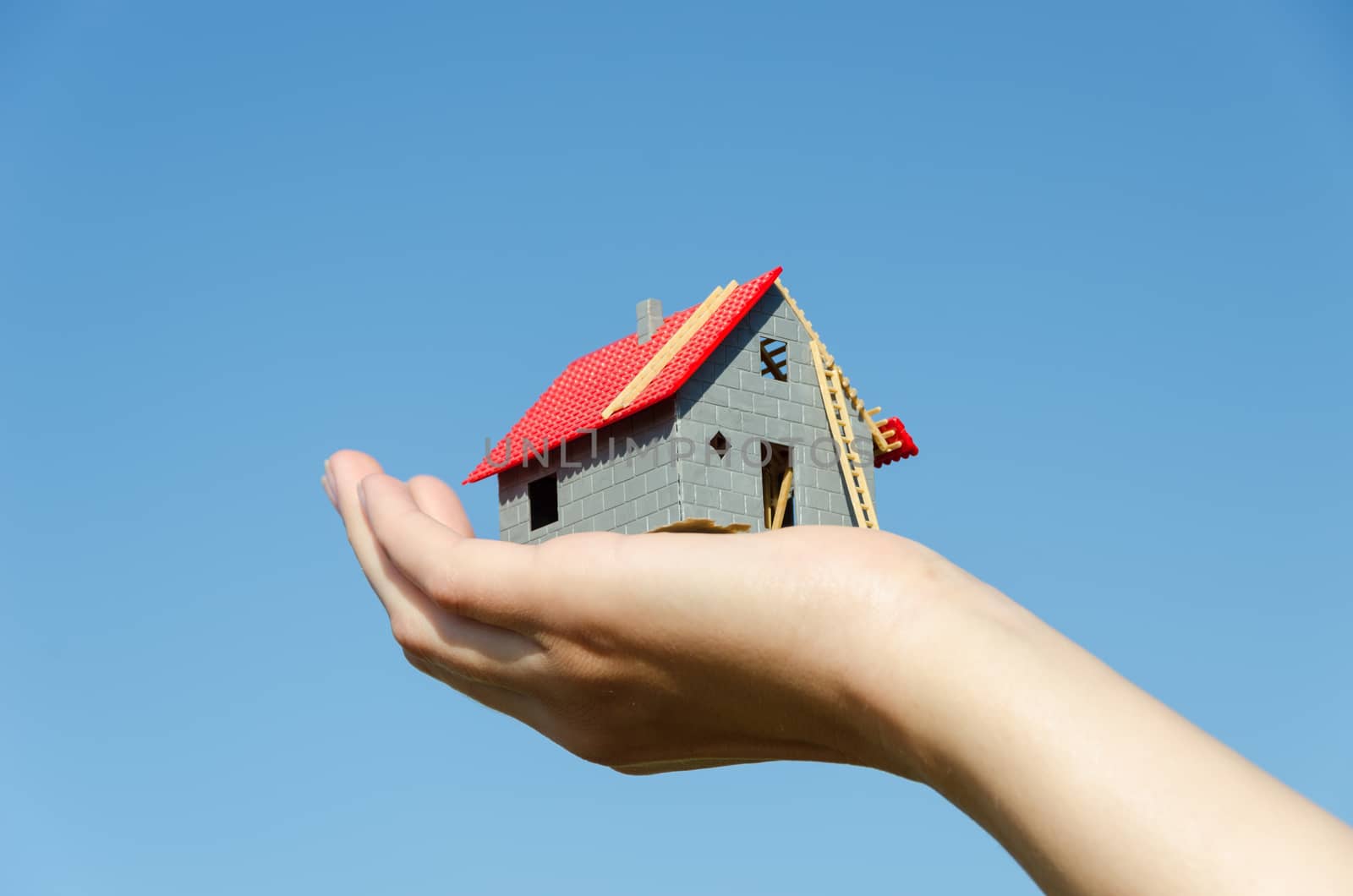 house miniature model in female palm on blue sky background, new house purchase concept