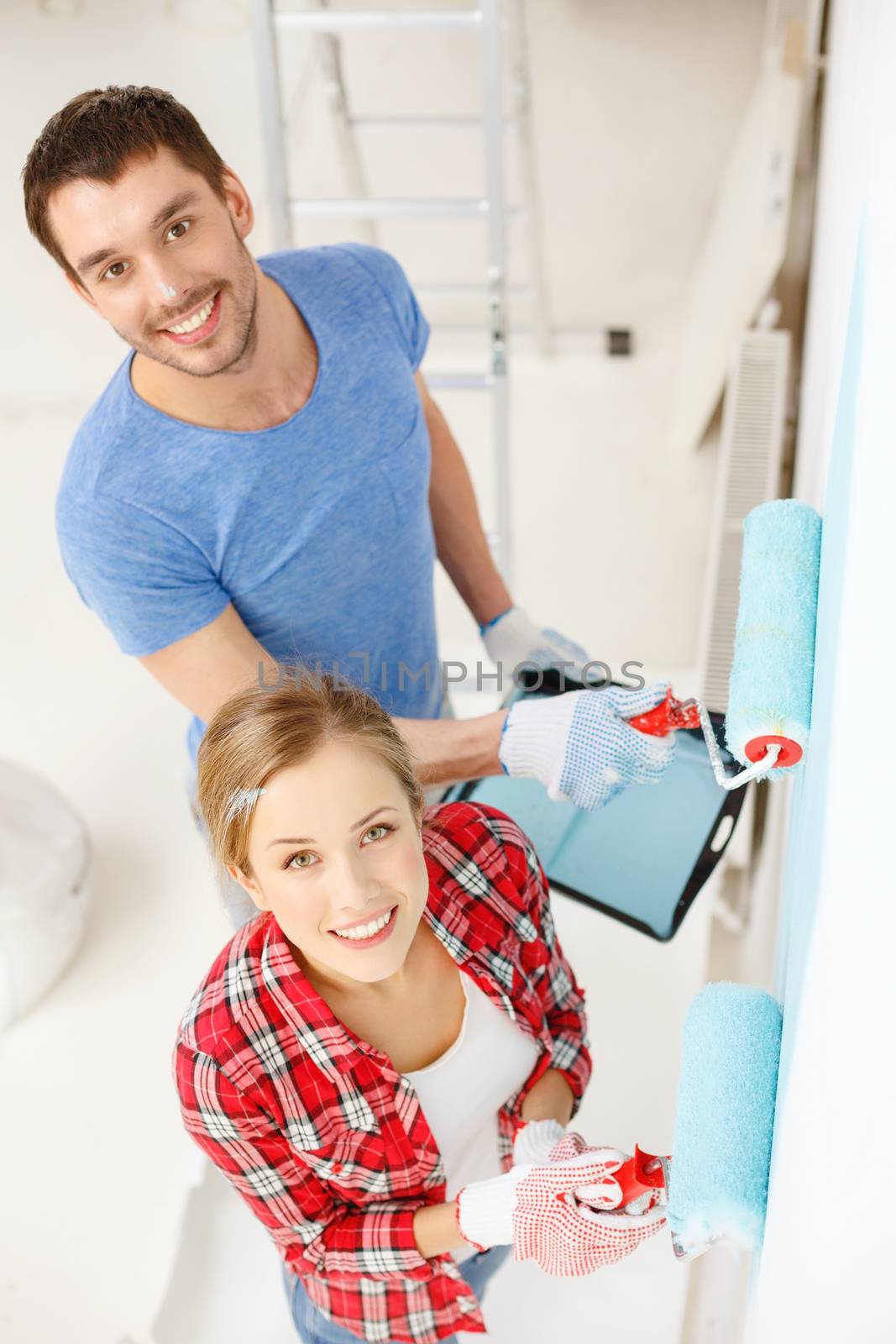 smiling couple painting wall at home by dolgachov