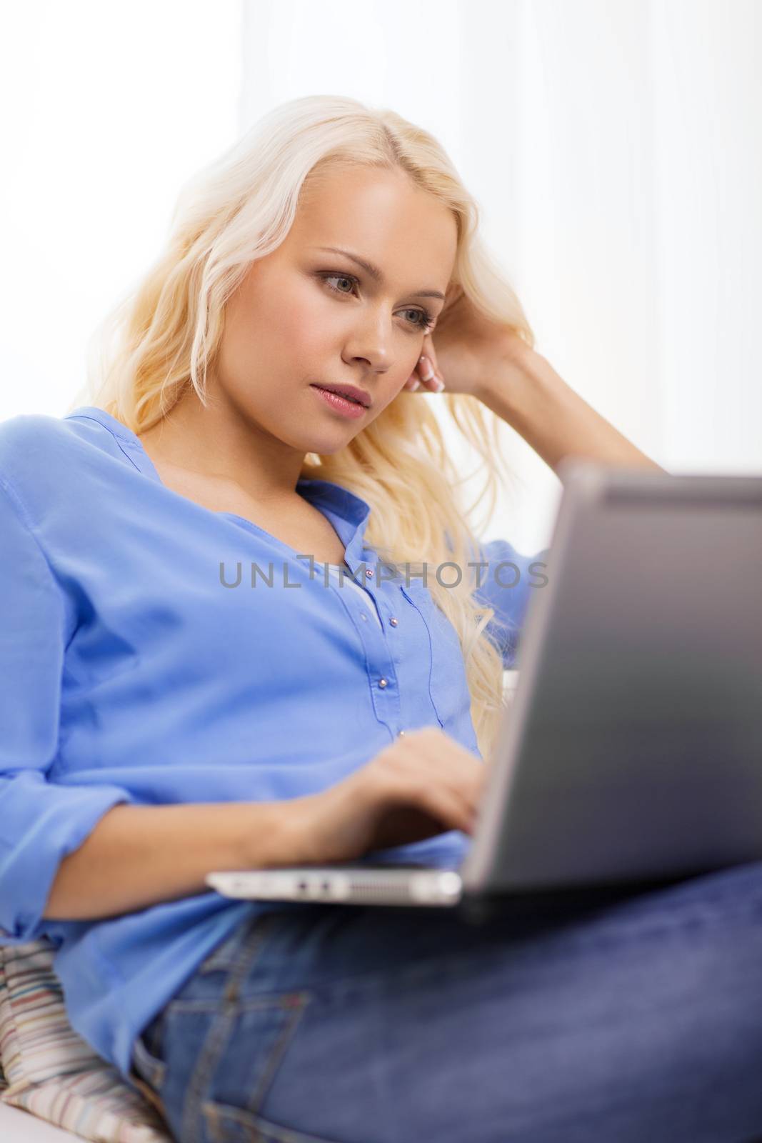 home, technology and internet concept - woman sitting on the couch with laptop computer at home