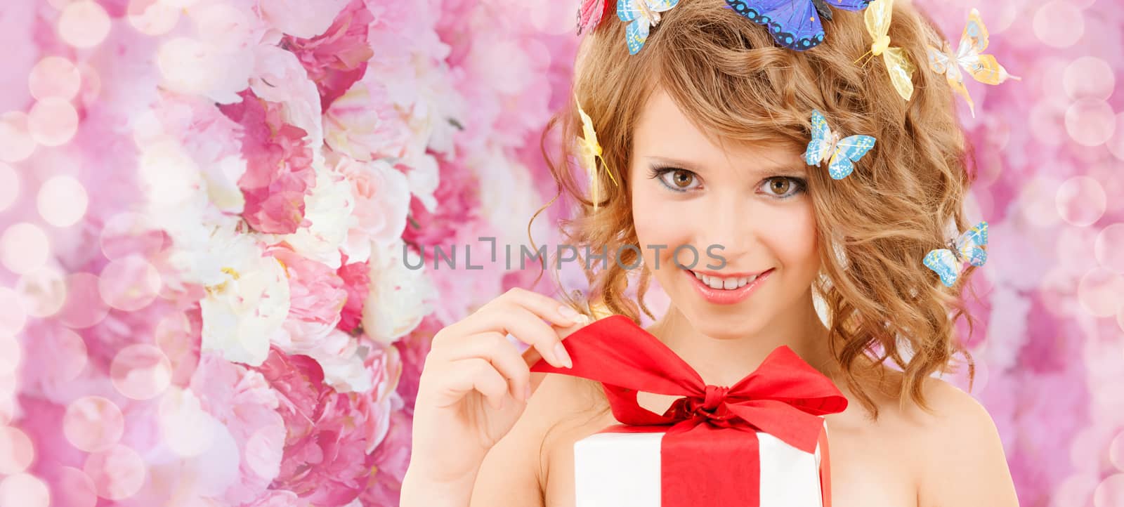 health, holidays and beauty concept - happy teenage girl with butterflies in hair opening gift box