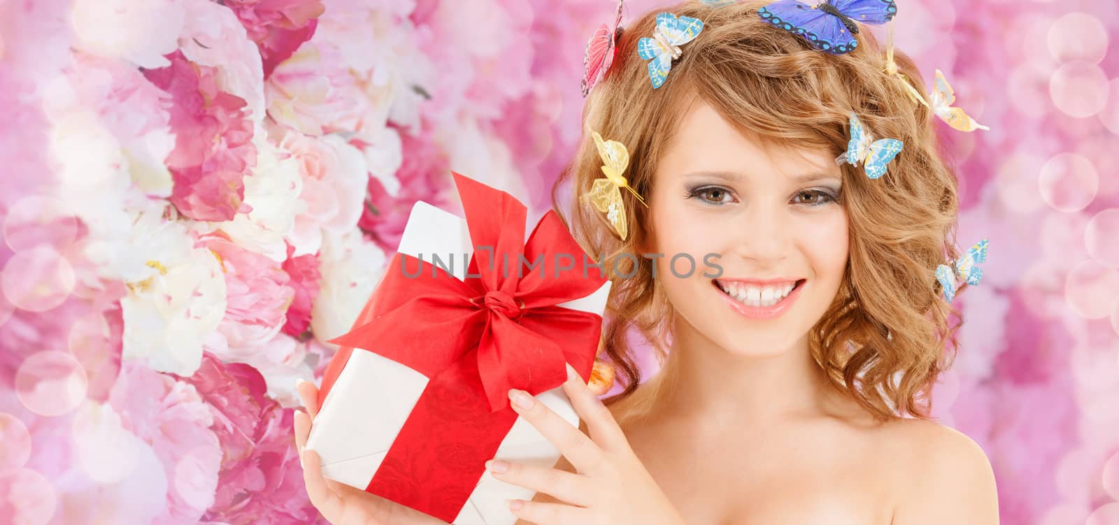 health, holidays and beauty concept - happy teenage girl with butterflies in hair showing gift box