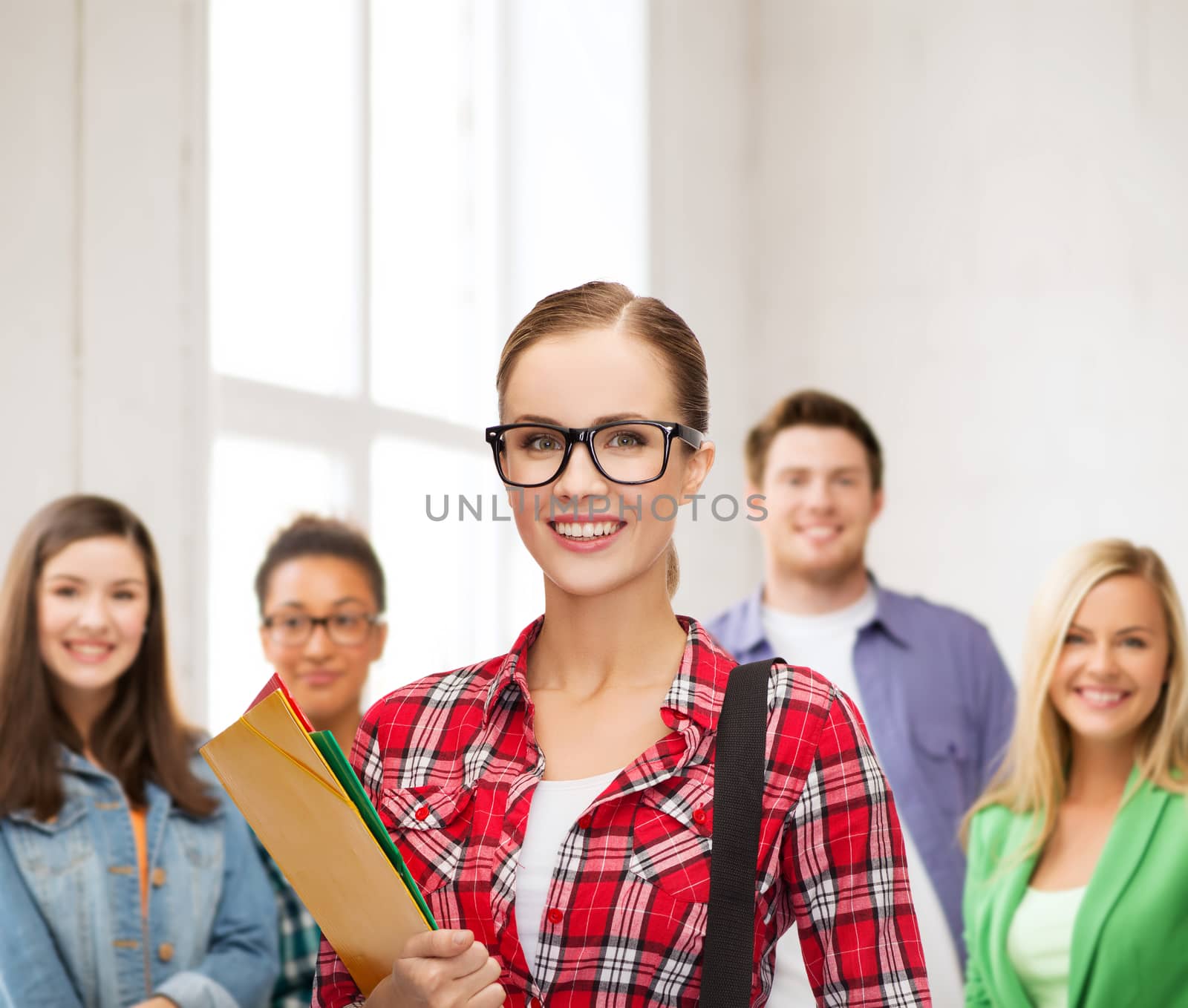 education and people concept - female student in eyeglasses with bag and folders