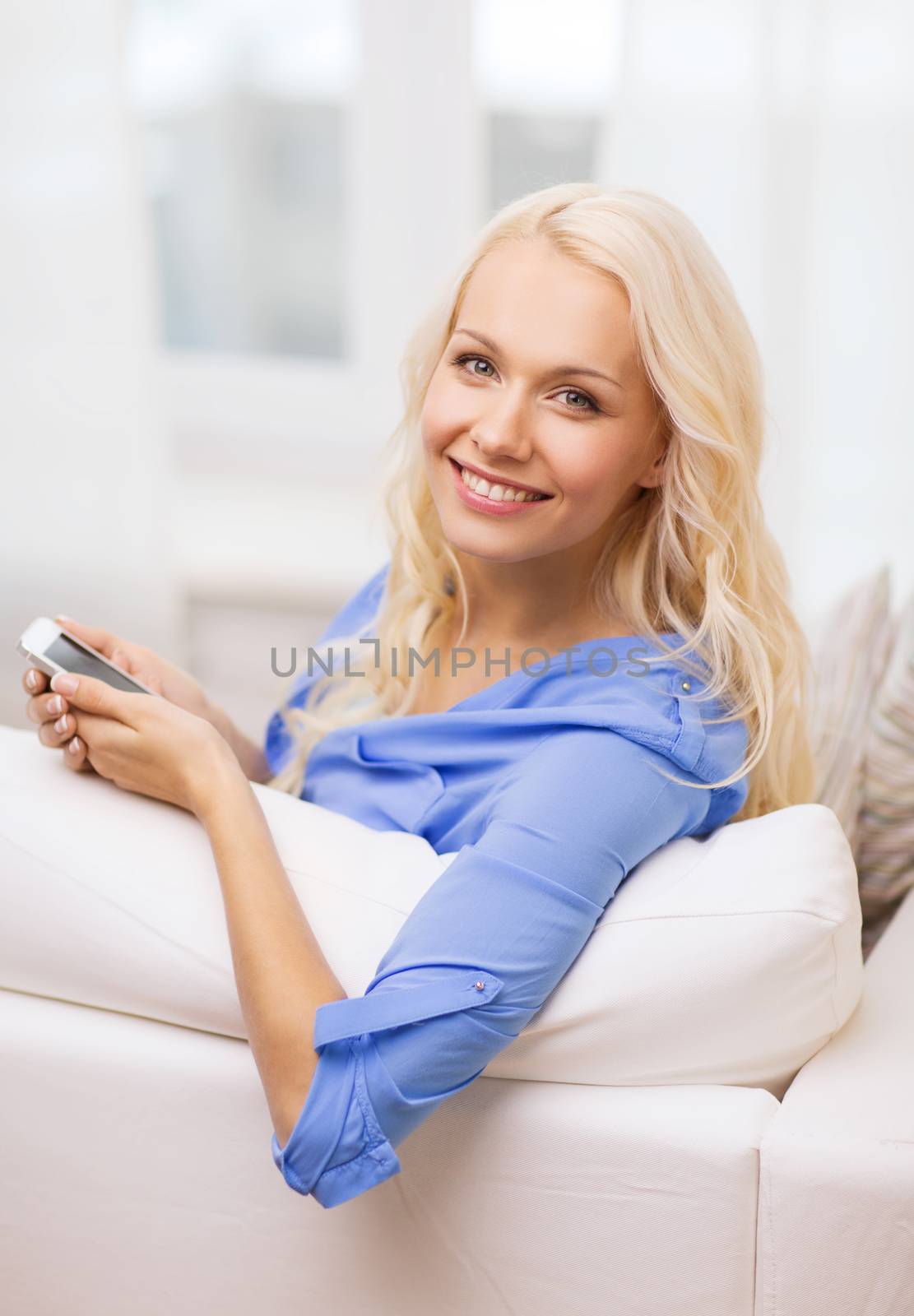 smiling woman with smartphone at home by dolgachov