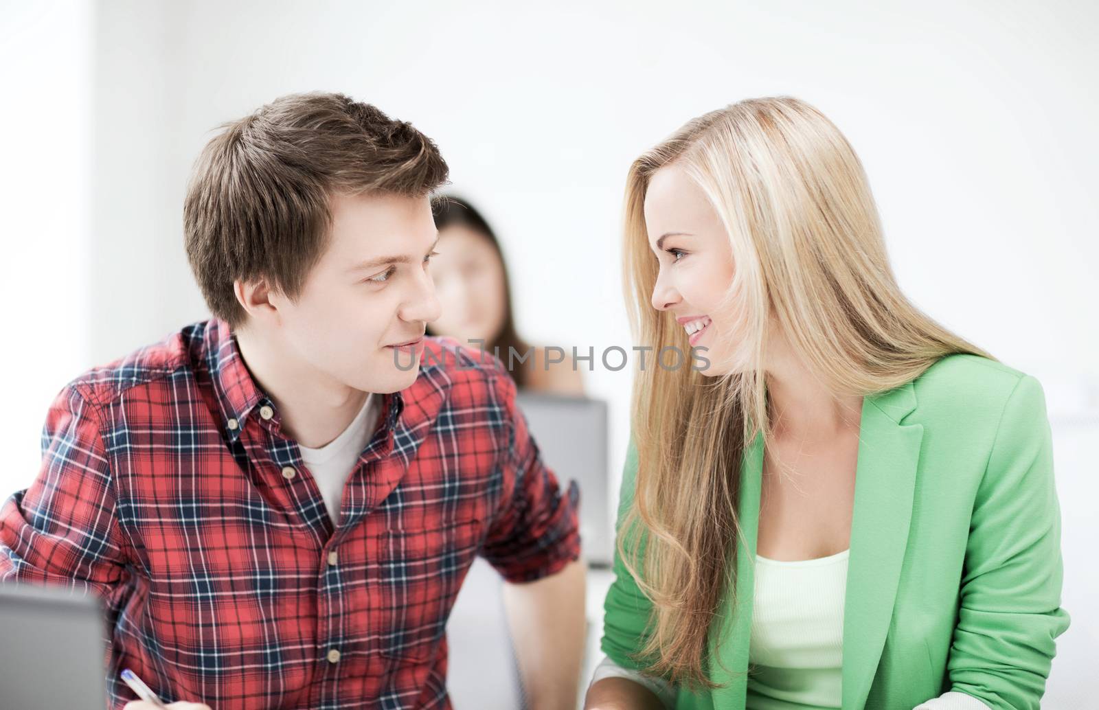 smiling students looking at each other at school by dolgachov