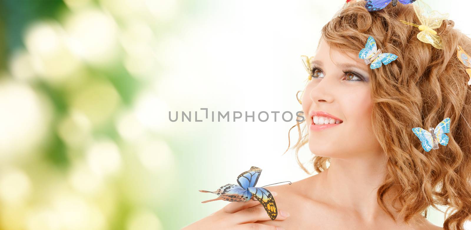 health and beauty concept - happy teenage girl with butterflies in hair and one sitting on her hand