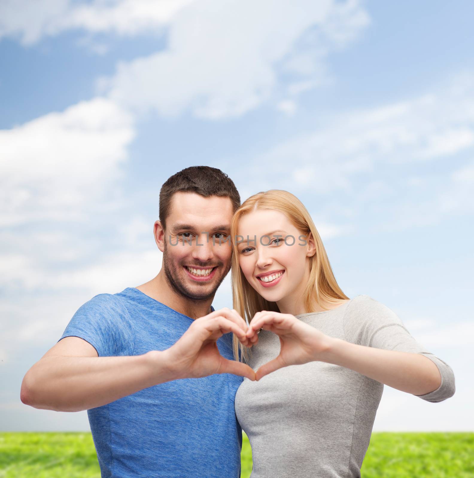 smiling couple showing heart with hands by dolgachov