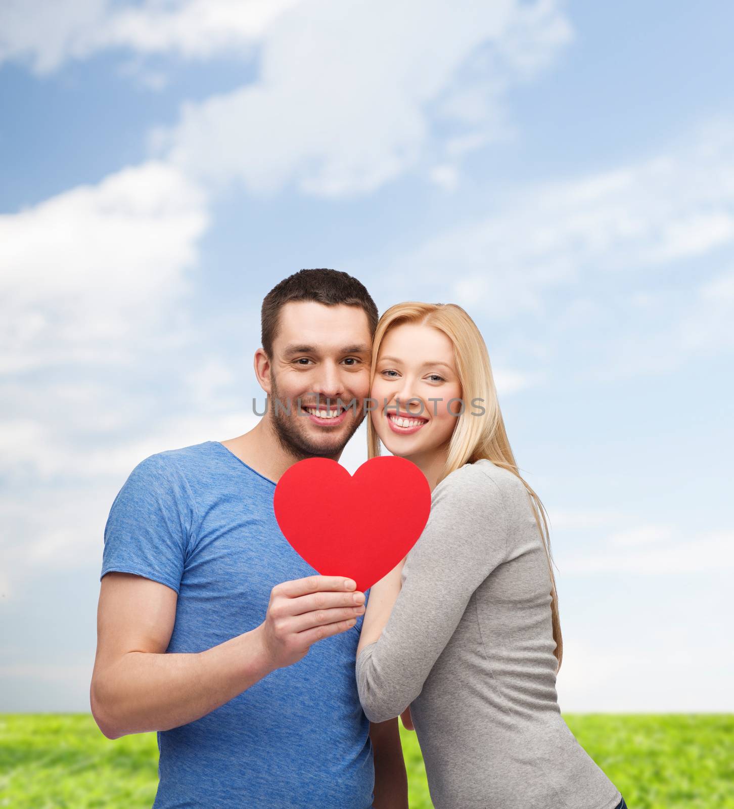 smiling couple holding big red heart by dolgachov