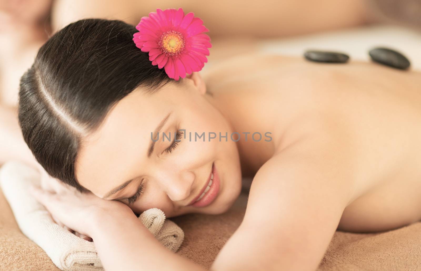 healthcare and beauty concept - picture of woman in spa salon with hot stones