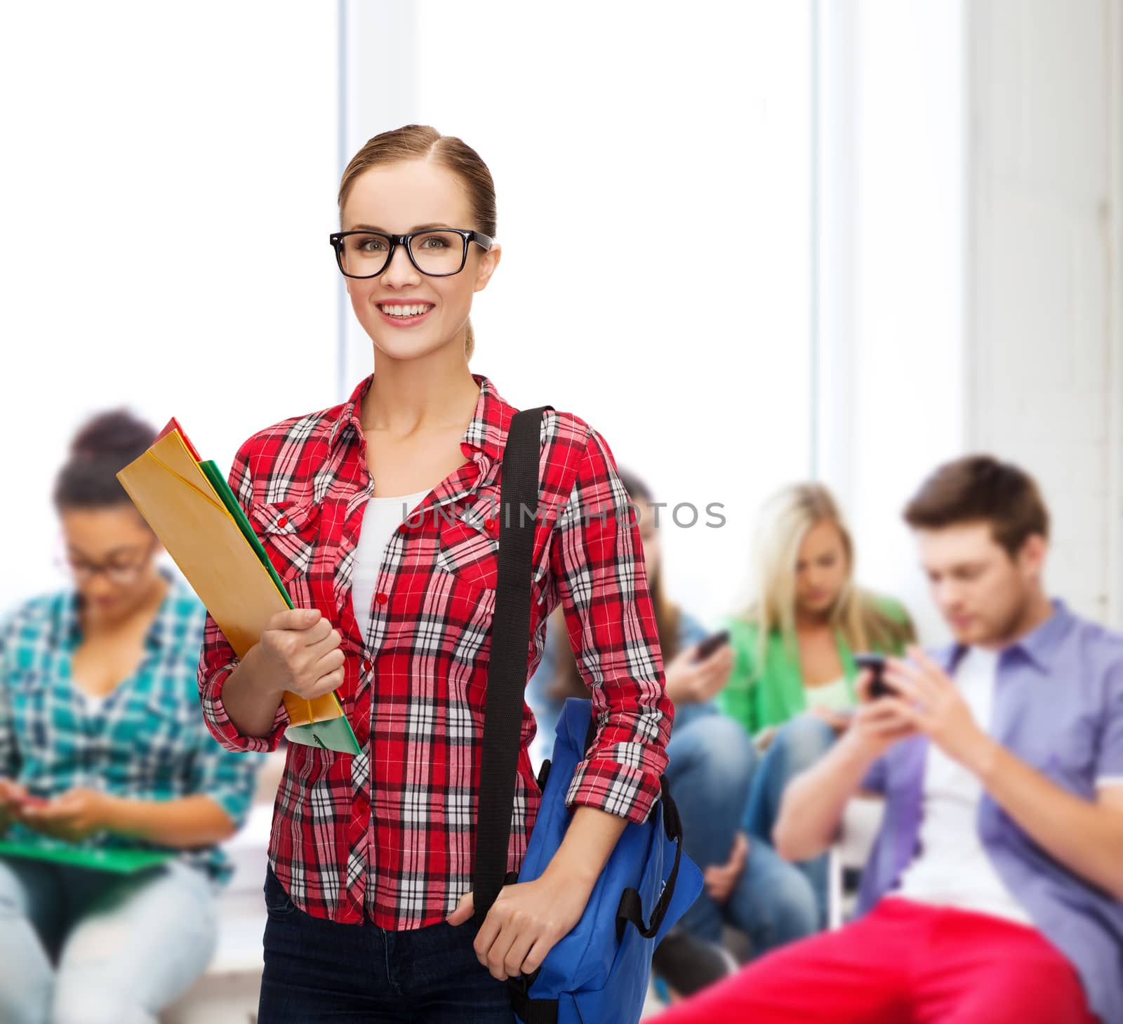 education and people concept - female student in eyeglasses with bag and folders