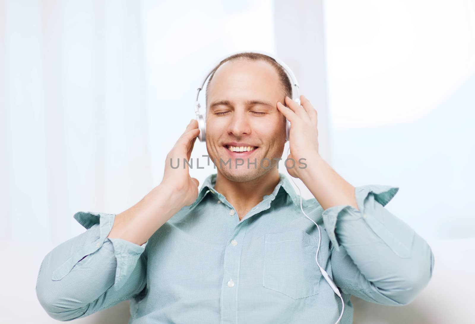 smiling man with headphones listening to music by dolgachov