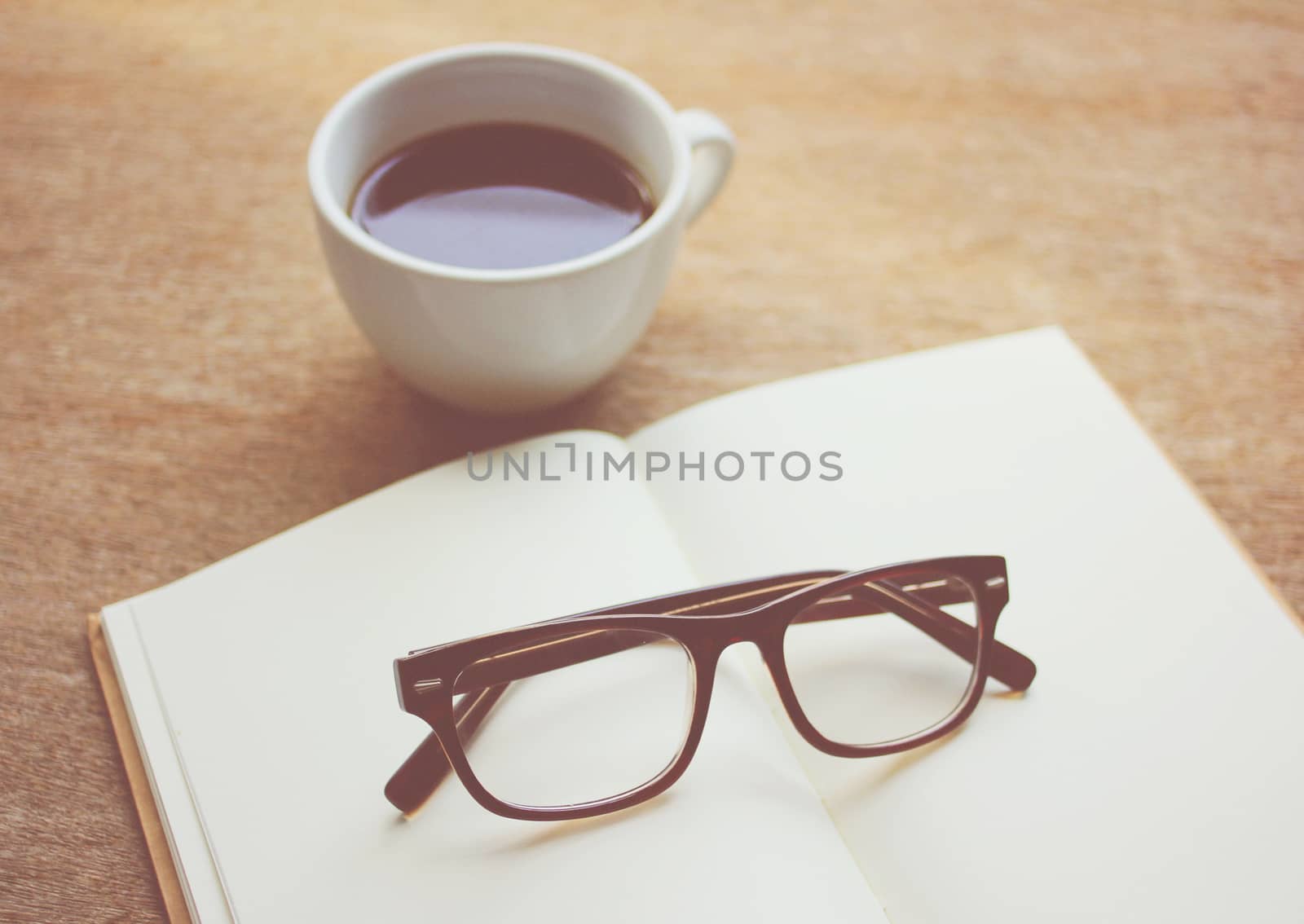 Eyeglasses on notebook and black coffee, retro filter effect