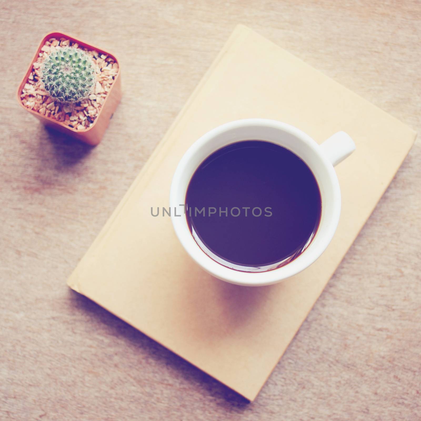 Black coffee on notebook and cactus with retro filter effect