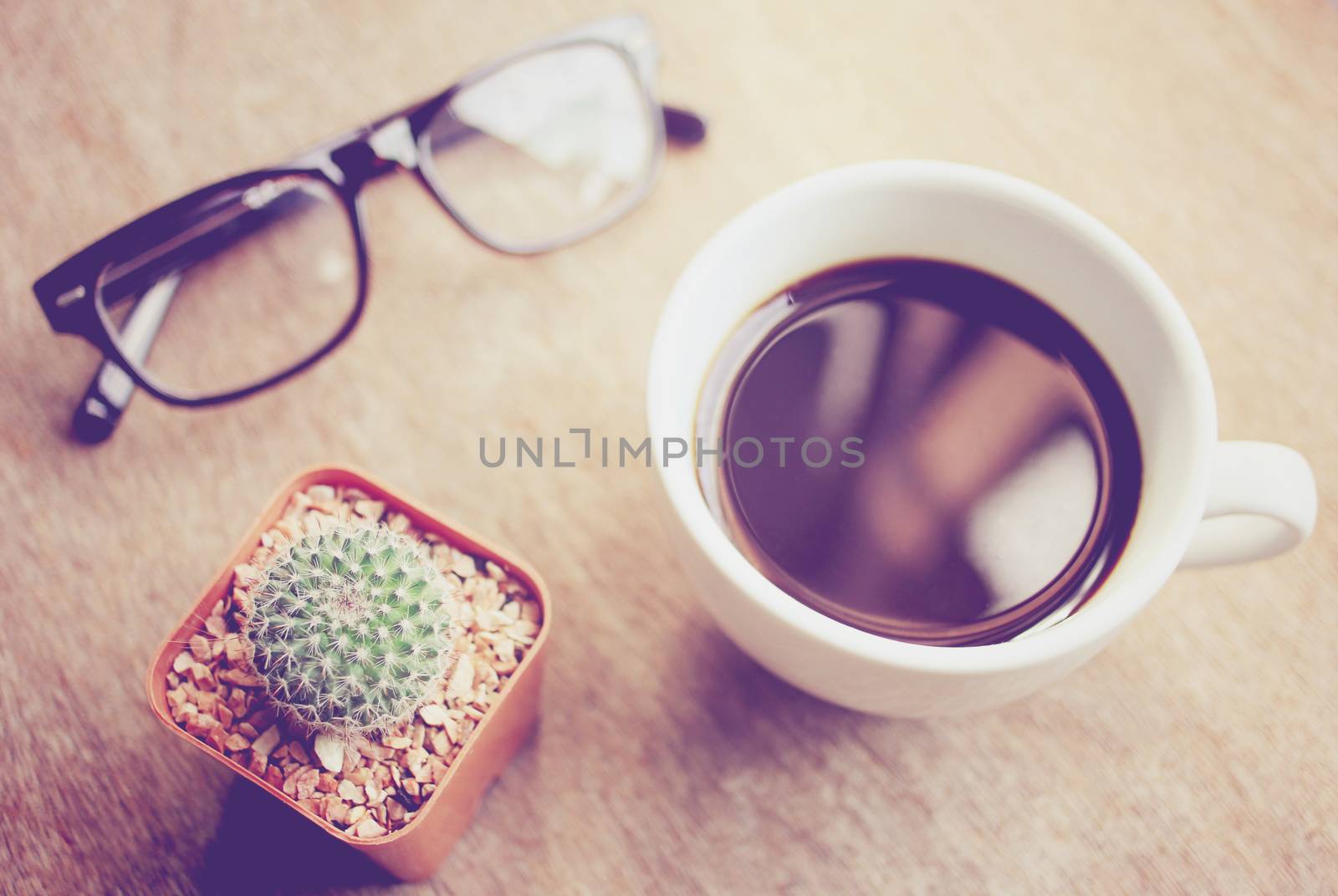 Black coffee and eyeglasses with cactus, retro filter effect