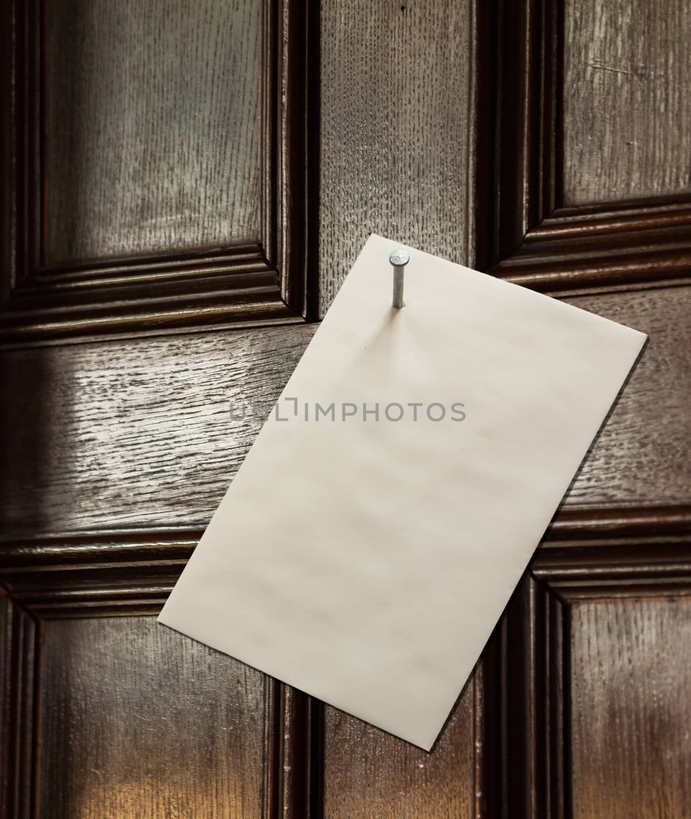 Envelope nailed to an old wooden door with a large nail in a threatening gesture from an angry person