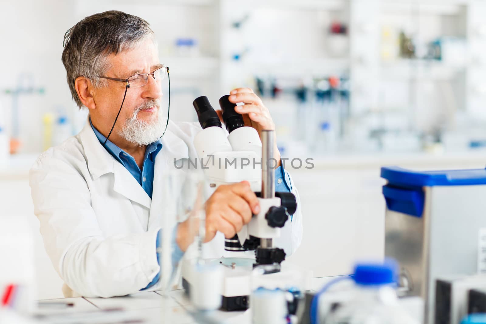 Senior male researcher carrying out scientific research in a lab using a microscope (shallow DOF; color toned image)