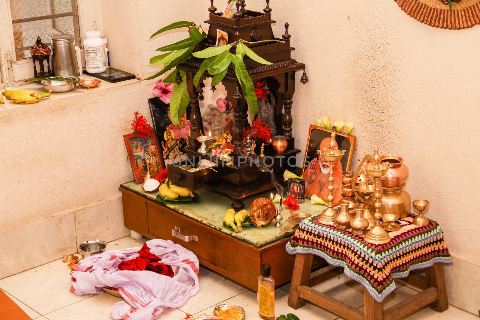 This is how a typical 'Puja Room' in any Hindu South Indian Family Home looks like after a traditional puja or prayer ceremony has been completed. There are always multiple icons , statues or photos of various sundry Gods and other paraphernalia used in the ceremony. the broken cocnut signifies completion of puja.