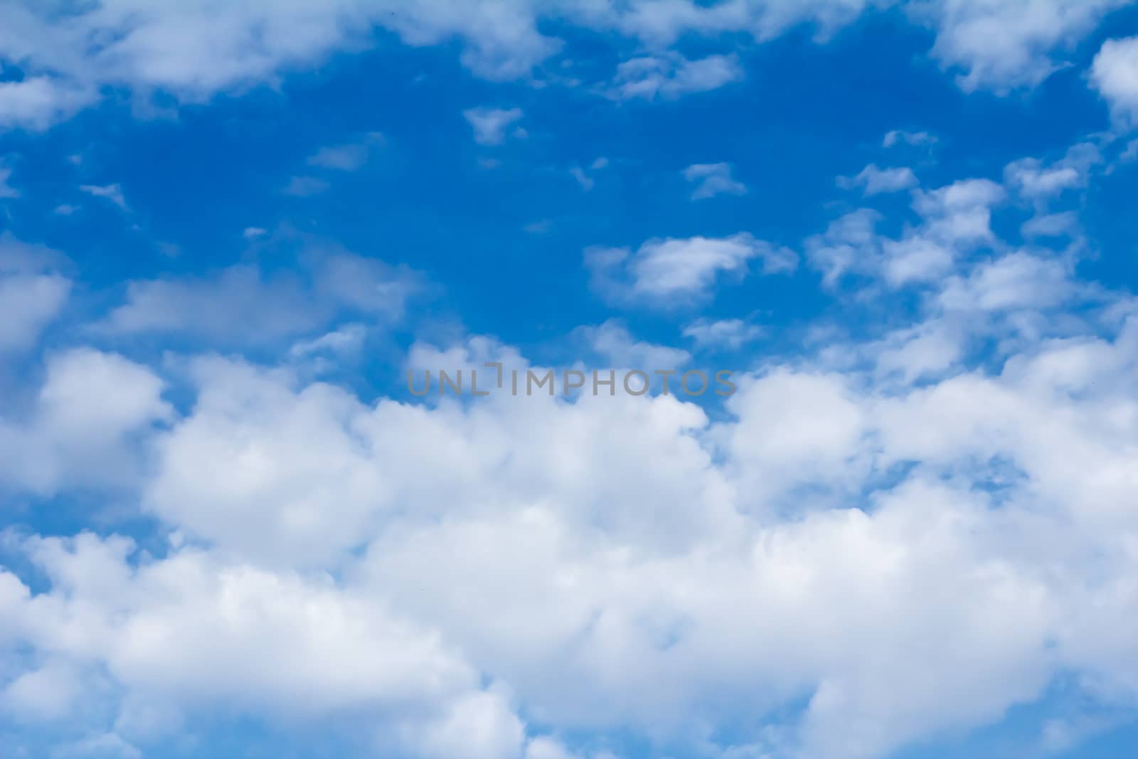 White fluffy clouds float on the blue sky in a clear sunny day.