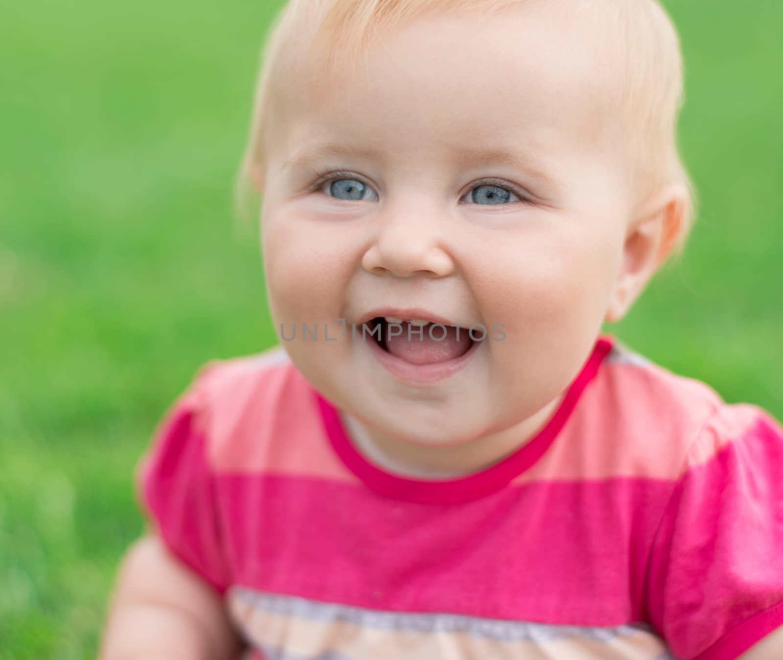 portrait of a smiling baby on a green lawn