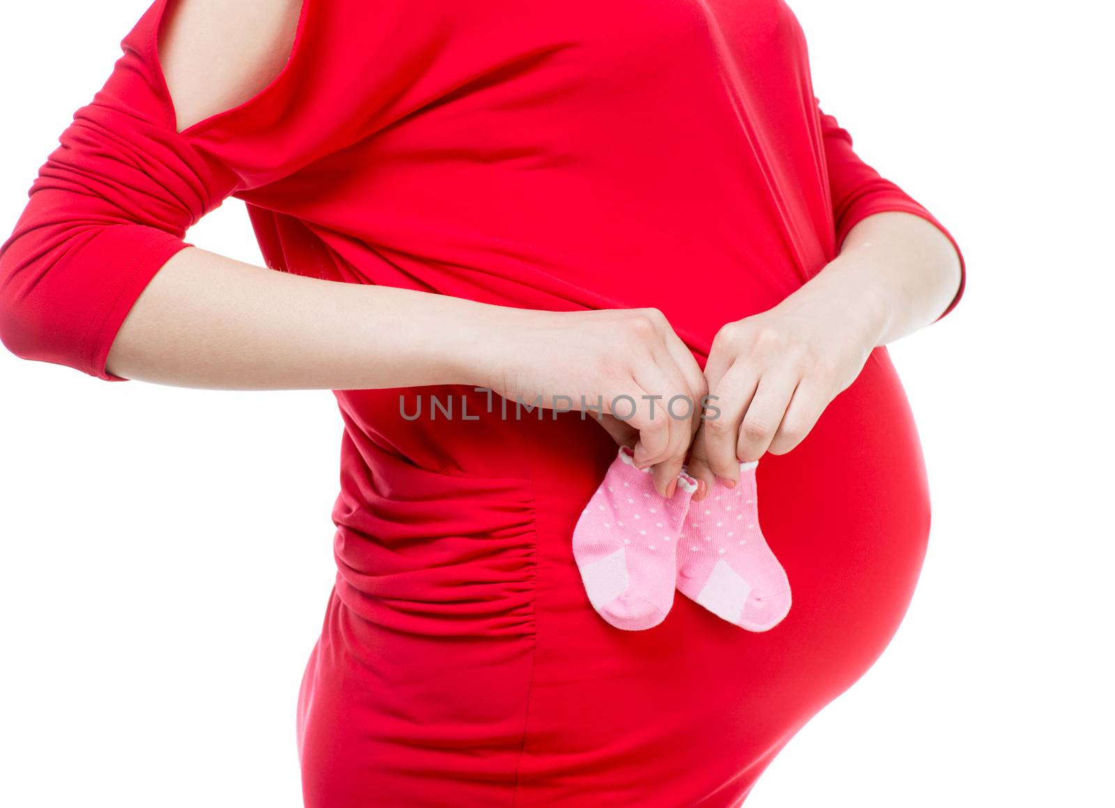 young pregnant woman in red dress holding baby socks isolated on white
