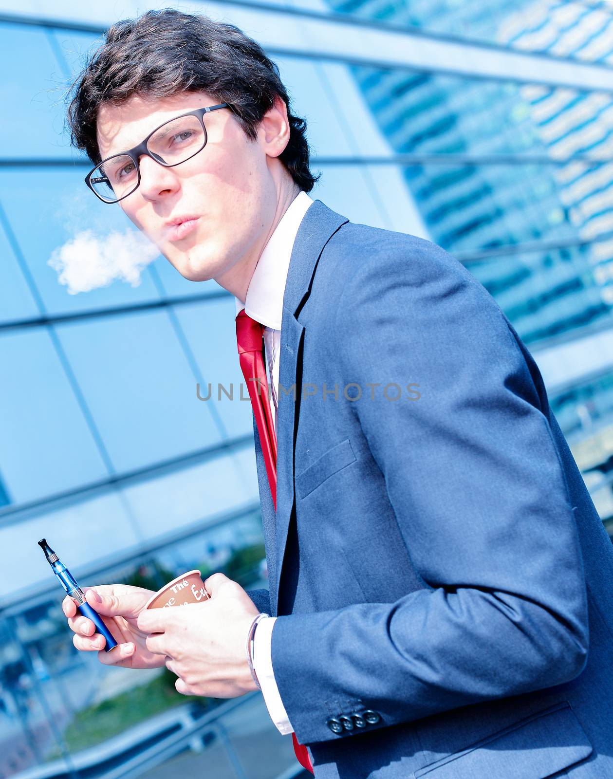 Nice portrait of young worker during coffee break with an electronic cigarette