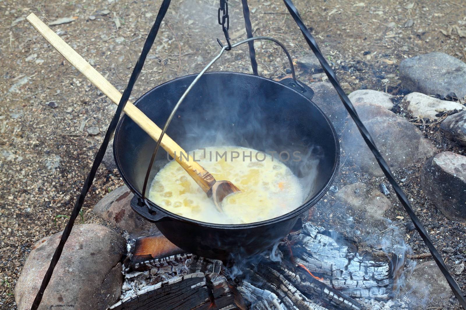 black pot on camp fire, cooking in big metallic cauldron outdoor 