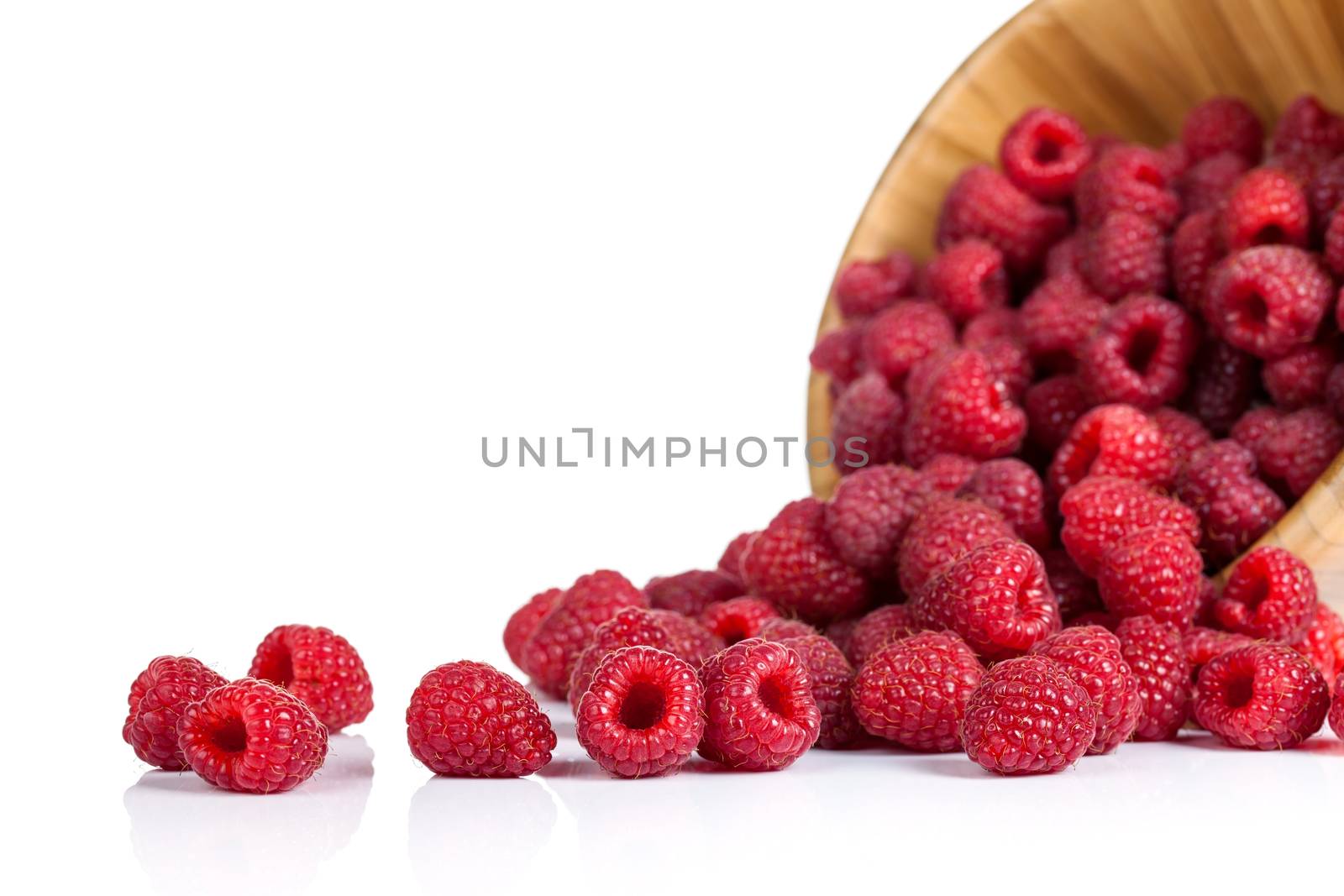 Raspberries in wooden bowl on white background