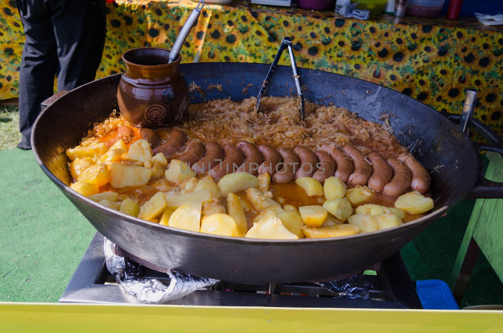 Potatoes, sausage and cabbage baked in a huge metal pan. Delicious organic meals in rural fair celebration.