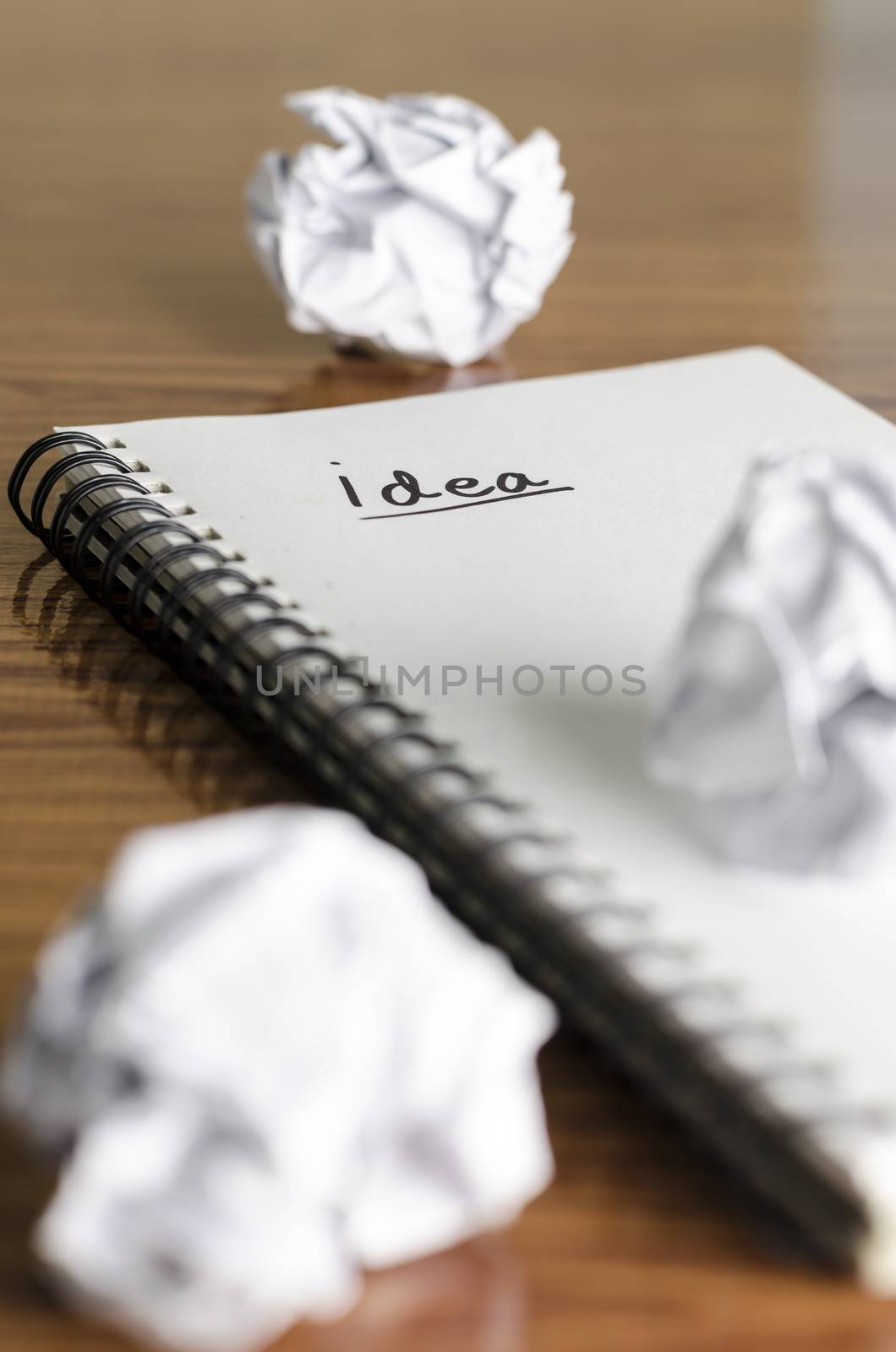 notebook write idea word with crumpled on wooden background