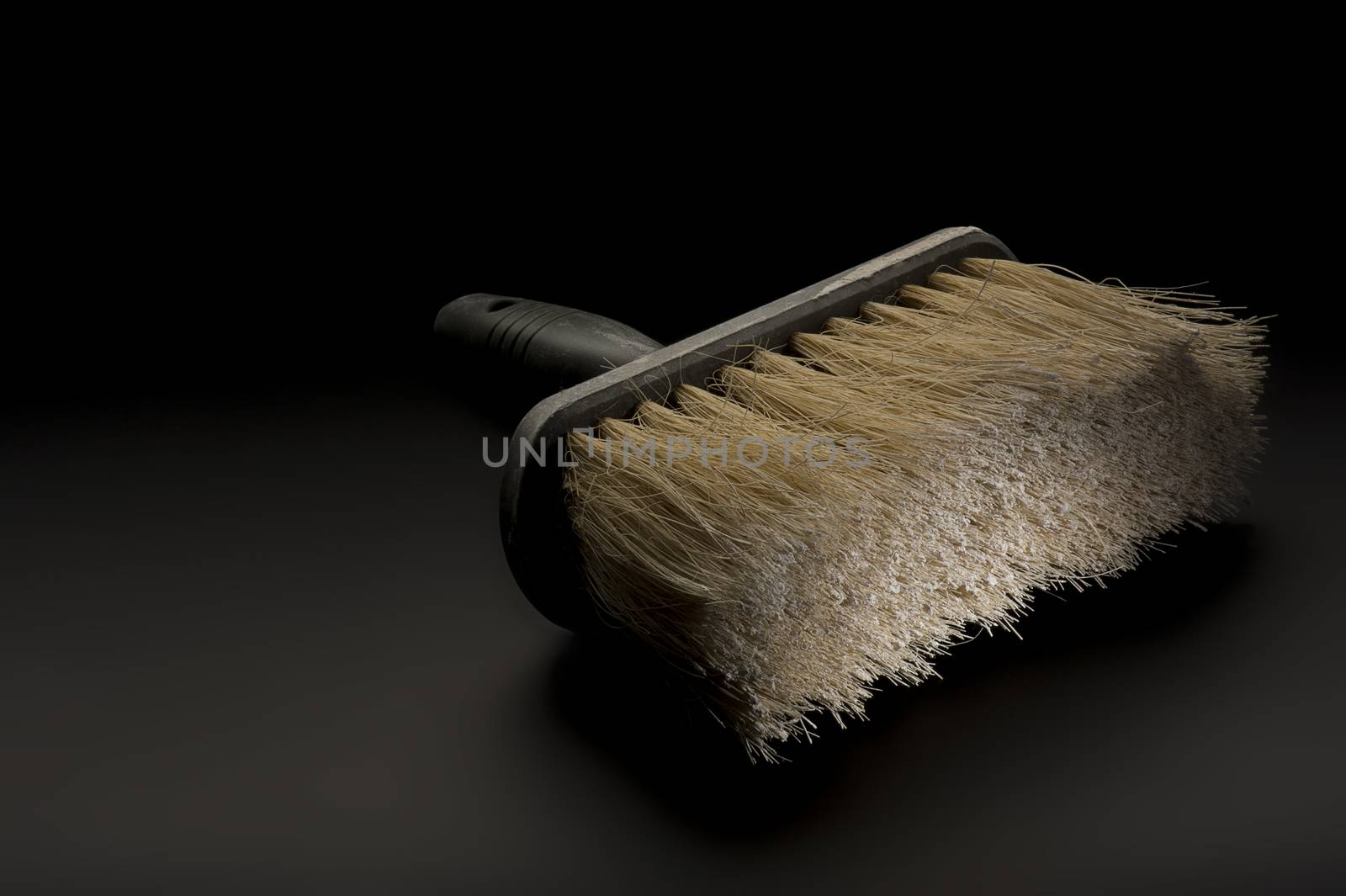 Close up view of a new clean large paintbrush or wallpapering brush lying on a dark background conceptual of DIY, home renovations, building and construction or interior decoration
