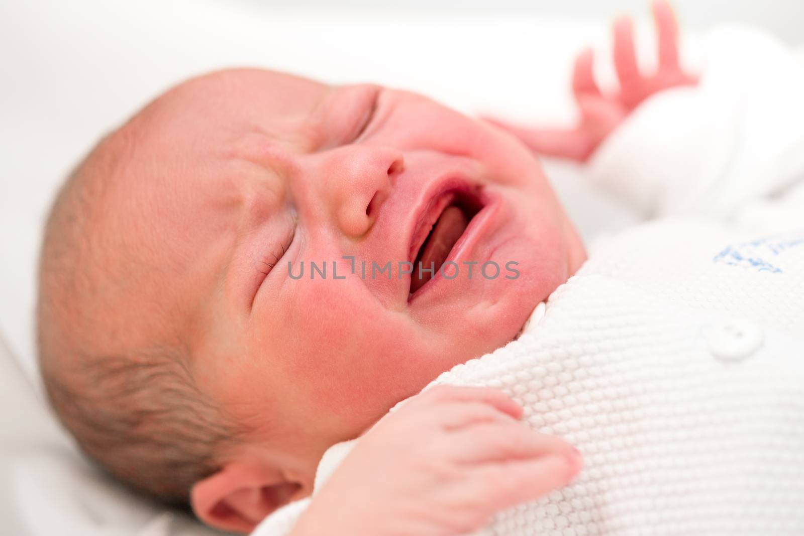 crying newborn baby in the hospital - the first hours of the new life