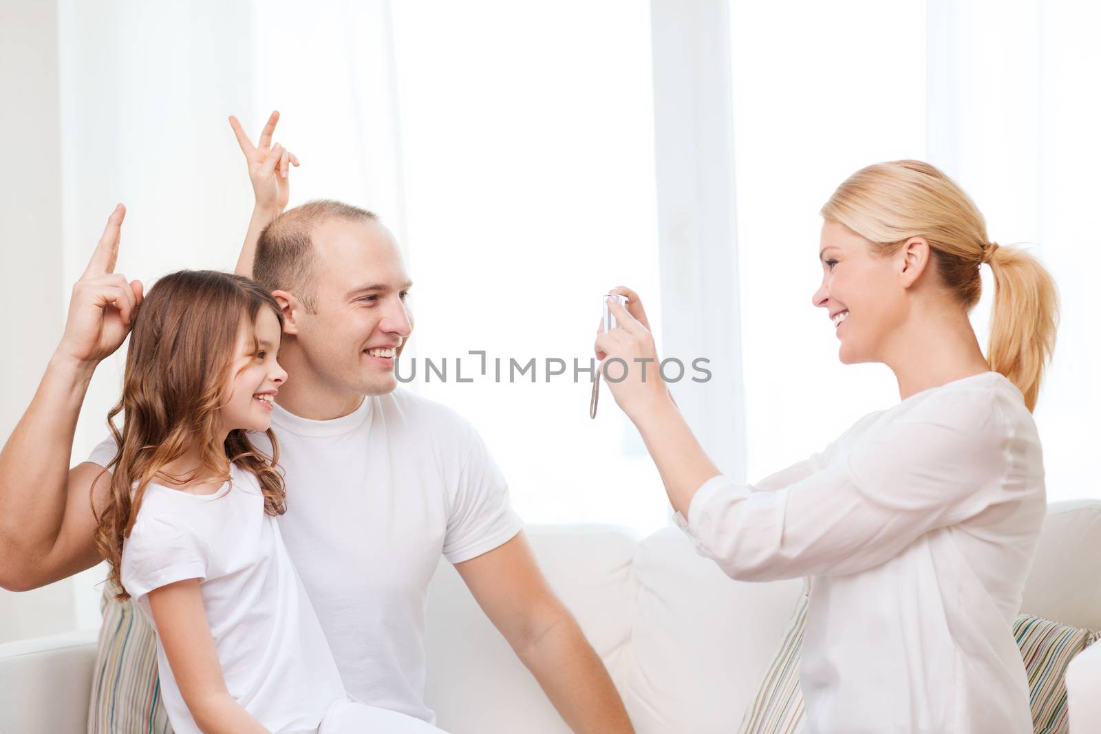 family, child, photography and home concept - smiling happy mother taking picture of father and daughter