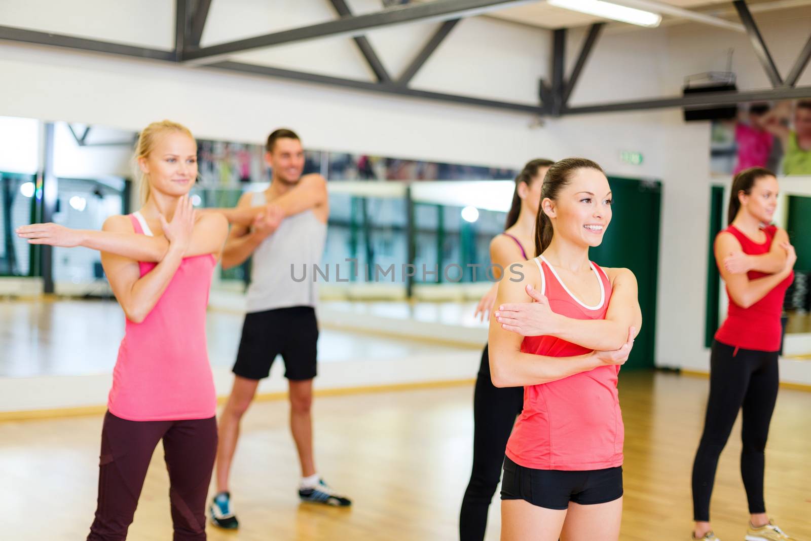 fitness, sport, training, gym and lifestyle concept - group of smiling people stretching in the gym