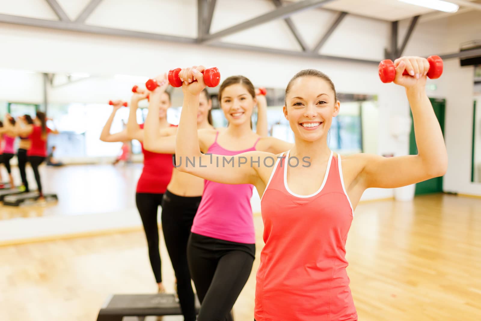 fitness, sport, training, gym and lifestyle concept - group of smiling female with dumbbells and aerobic step