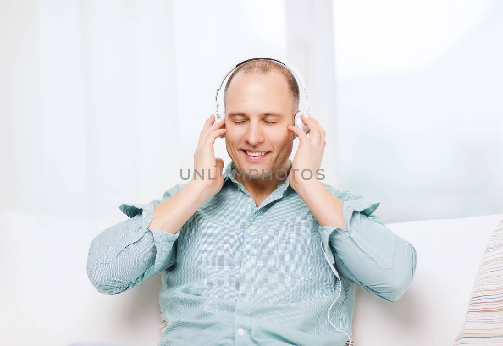 leisure and lifestyle concept - happy man with headphones listening to music at home