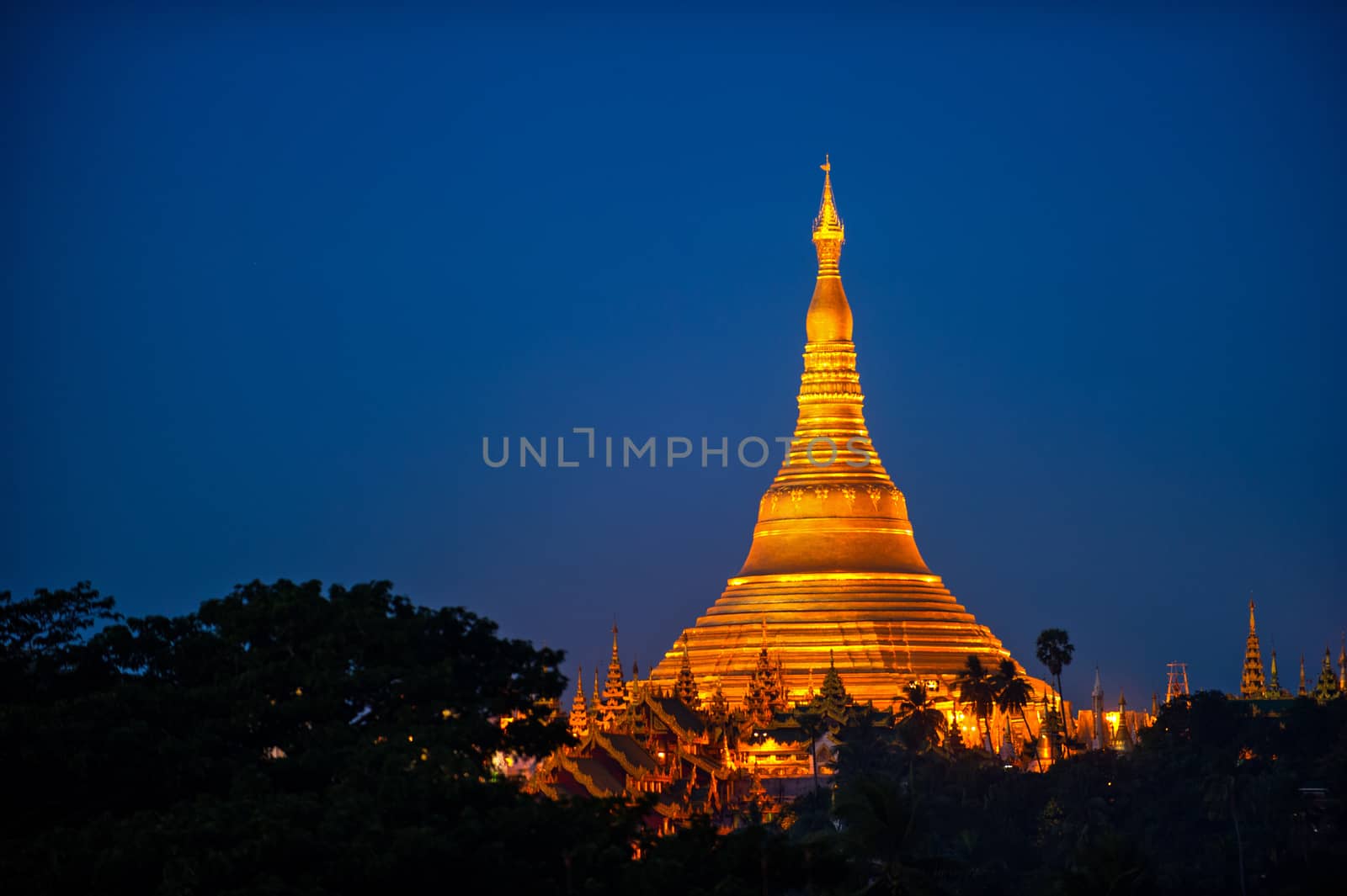 Shwedagon Pagoda Temple with village below in the twilight at Ya by think4photop