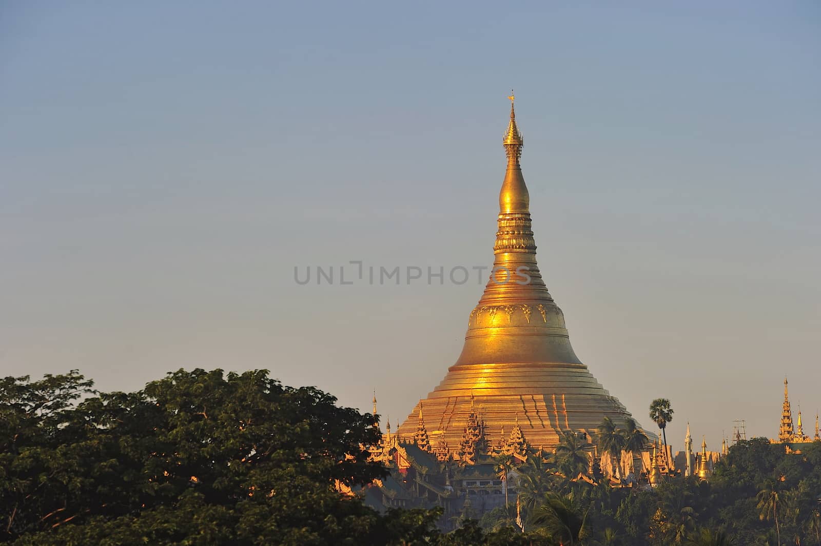 Shwedagon Pagoda Temple with village below in the morning light by think4photop