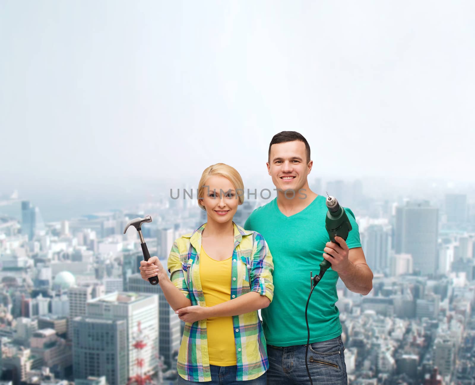 repair, construction and maintenance concept - smiling couple with hammer and drill over white background