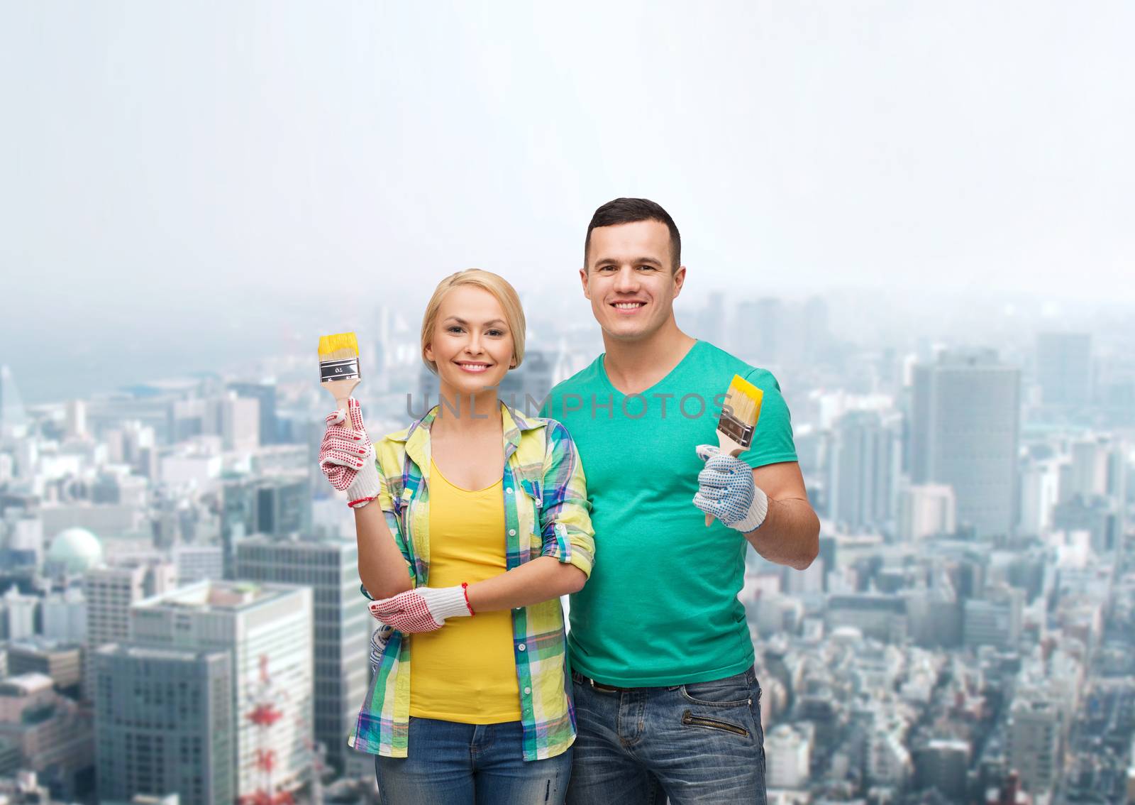 repair, construction and maintenance concept - smiling couple with paintbrush