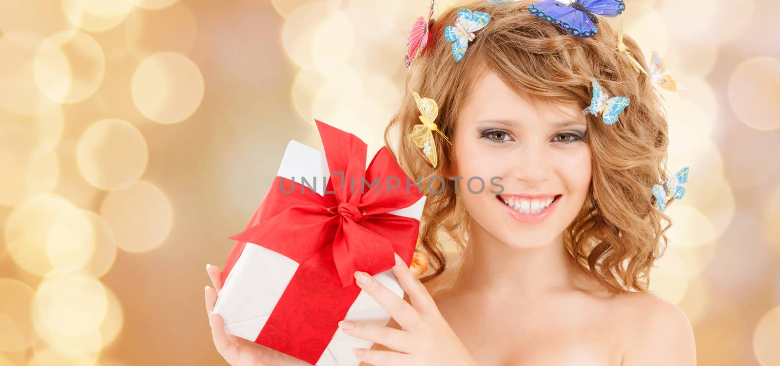 health, holidays and beauty concept - happy teenage girl with butterflies in hair showing gift box