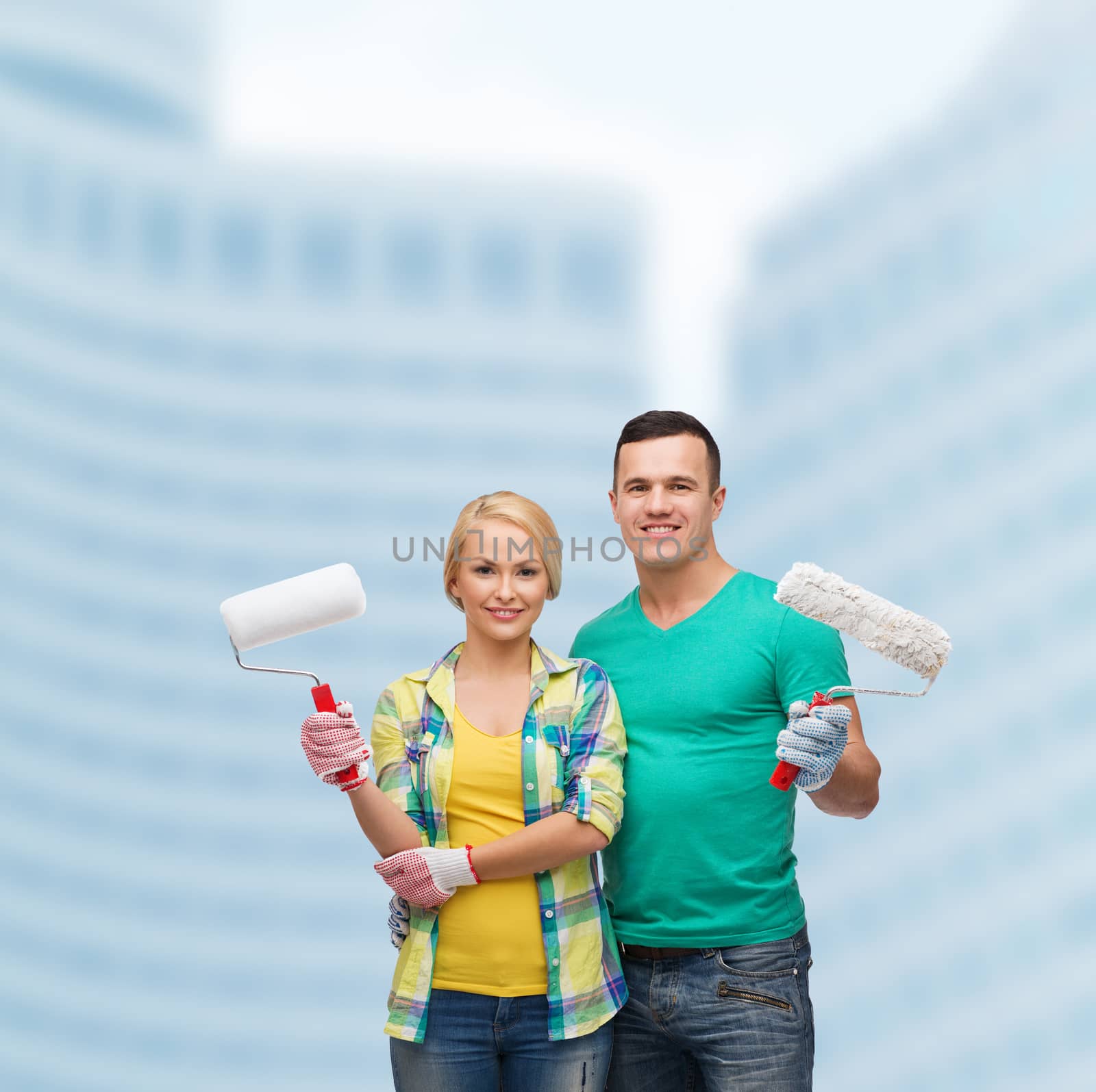 smiling couple in gloves with paint rollers by dolgachov