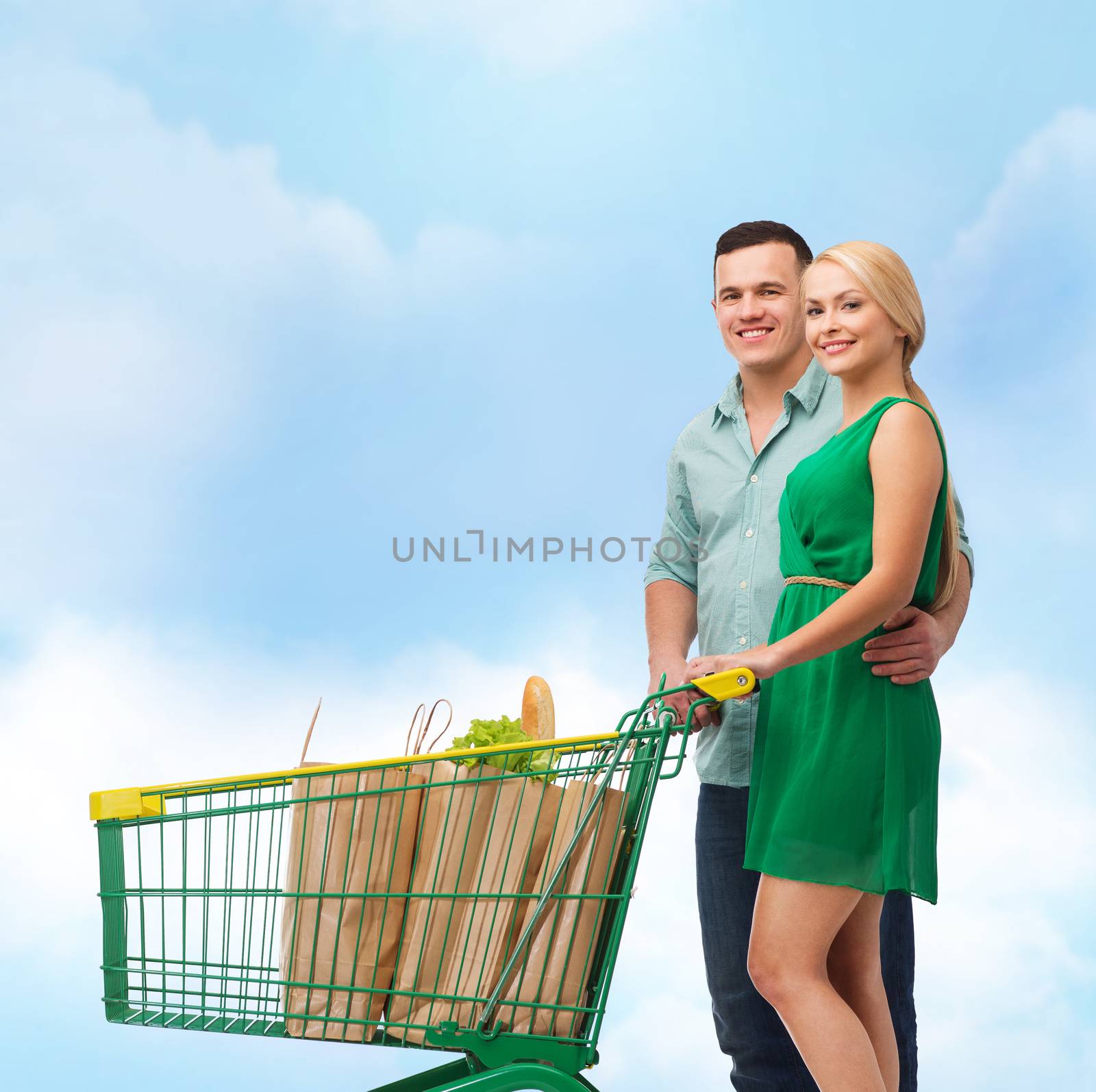 happiness, shopping and couple concept - smiling couple with shopping cart and food in it