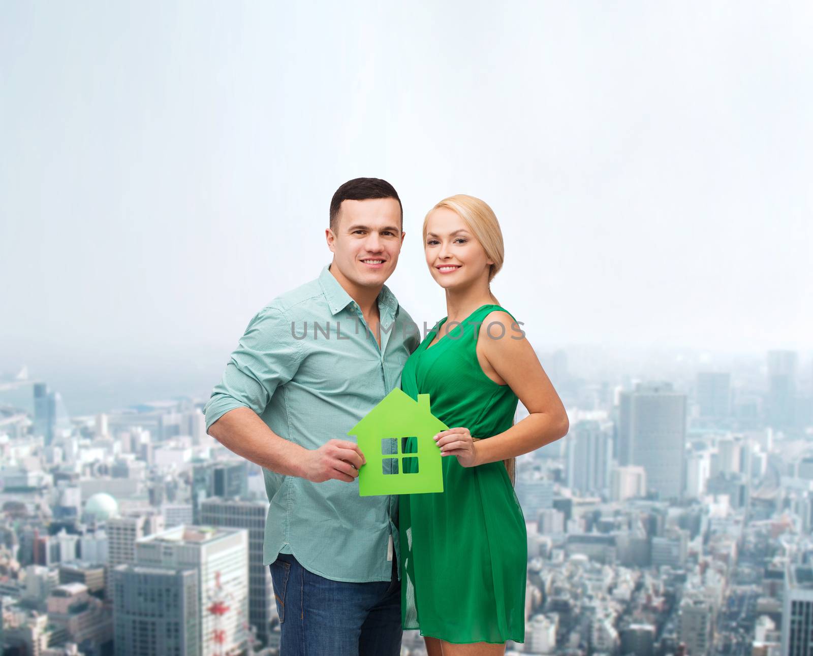 smiling couple holding green paper house by dolgachov