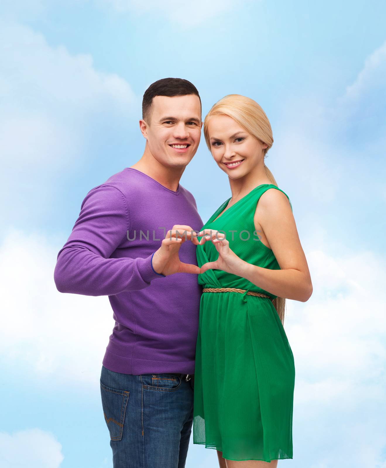 smiling couple showing heart with hands by dolgachov