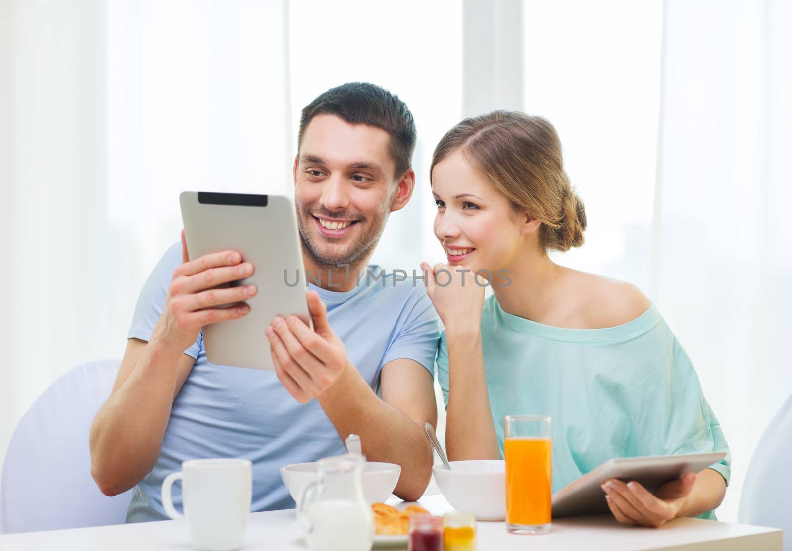 smiling couple with tablet pc reading news by dolgachov