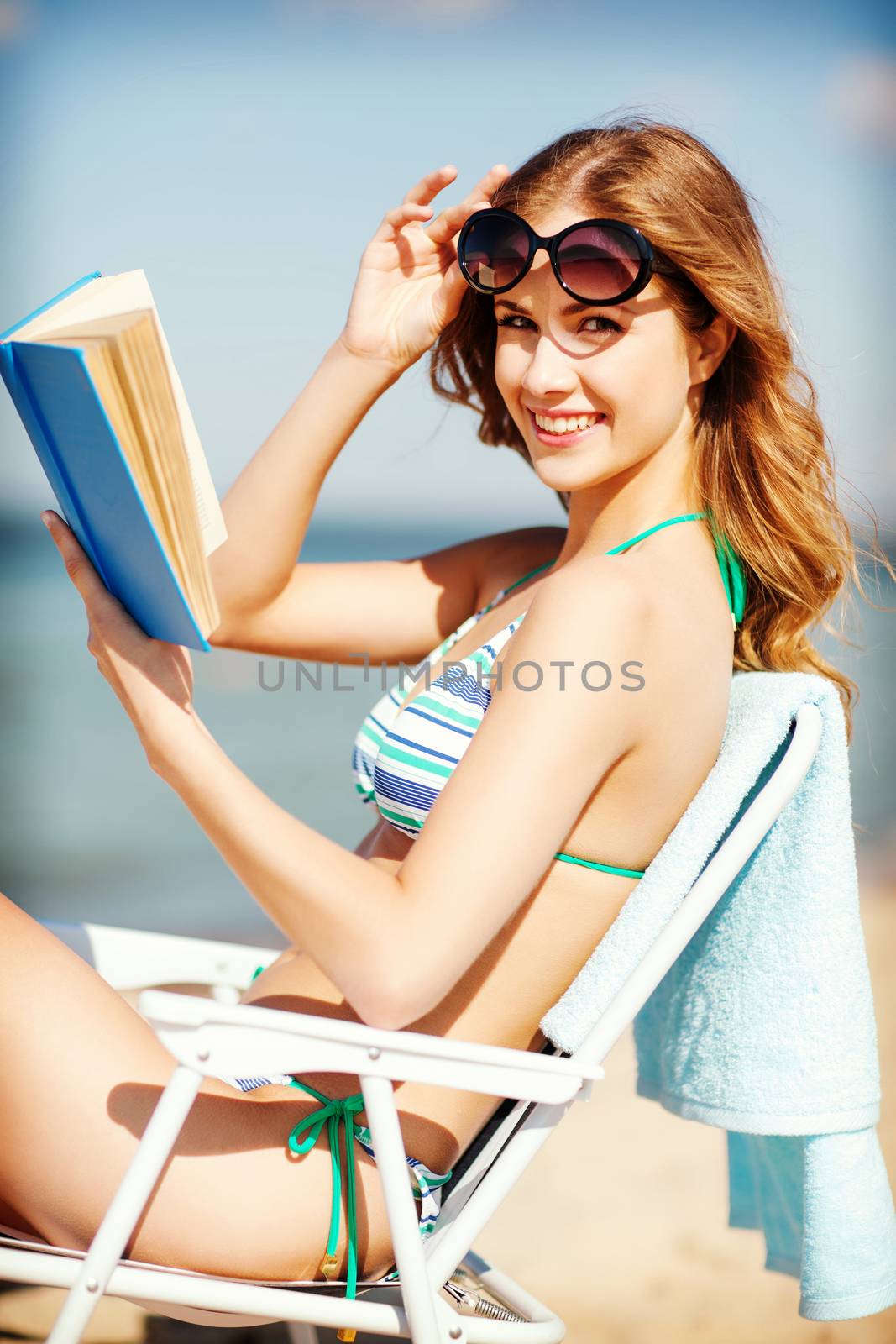 girl reading book on the beach chair by dolgachov
