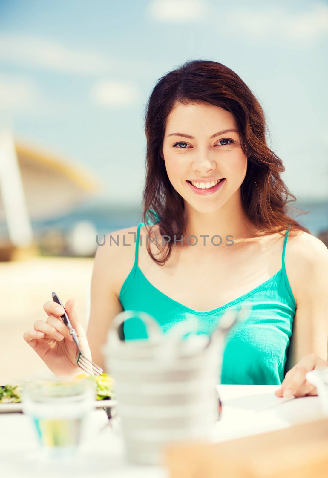 food, summer holidays and vacation - girl eating in cafe on the beach