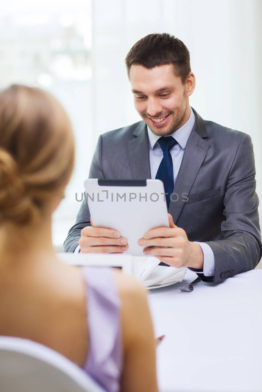 restaurant, couple, technology and holiday concept - smiling man looking at menu on tablet pc computer at restaurant