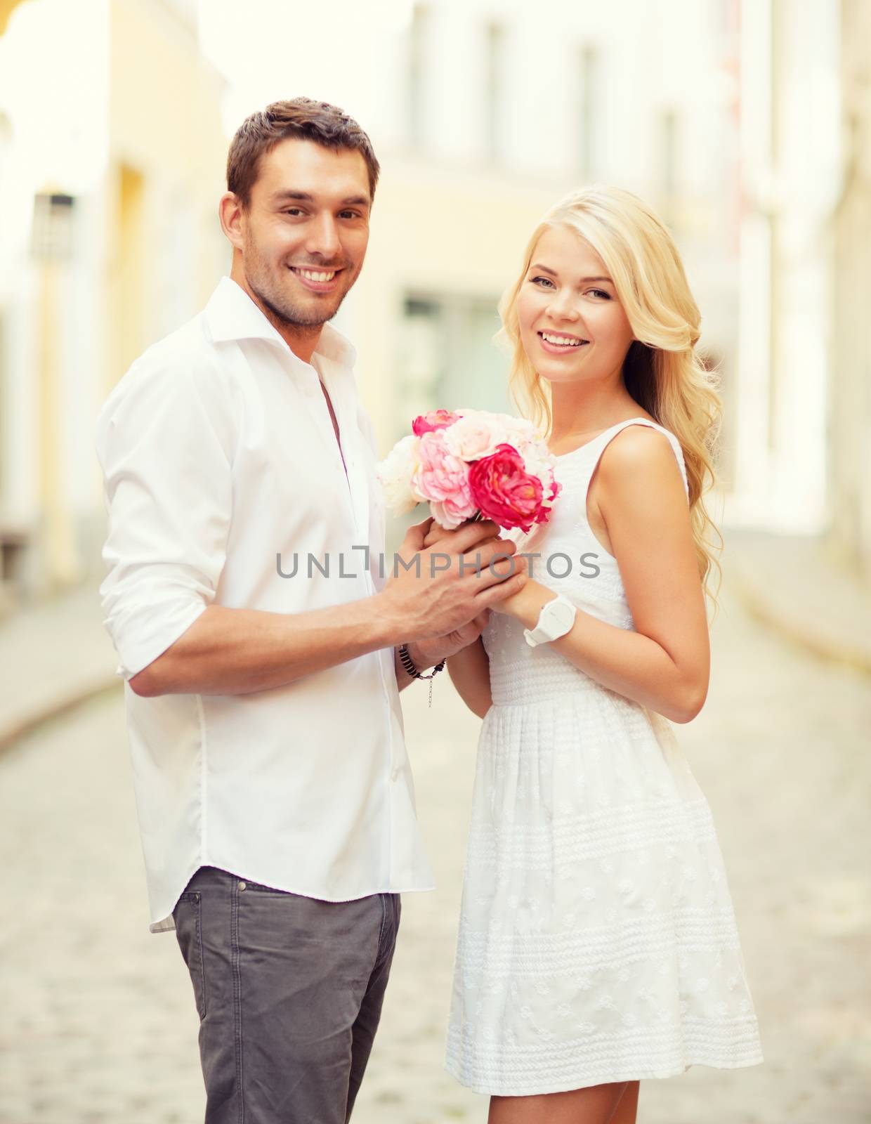 summer holidays and dating concept - couple with bouquet of flowers in the city