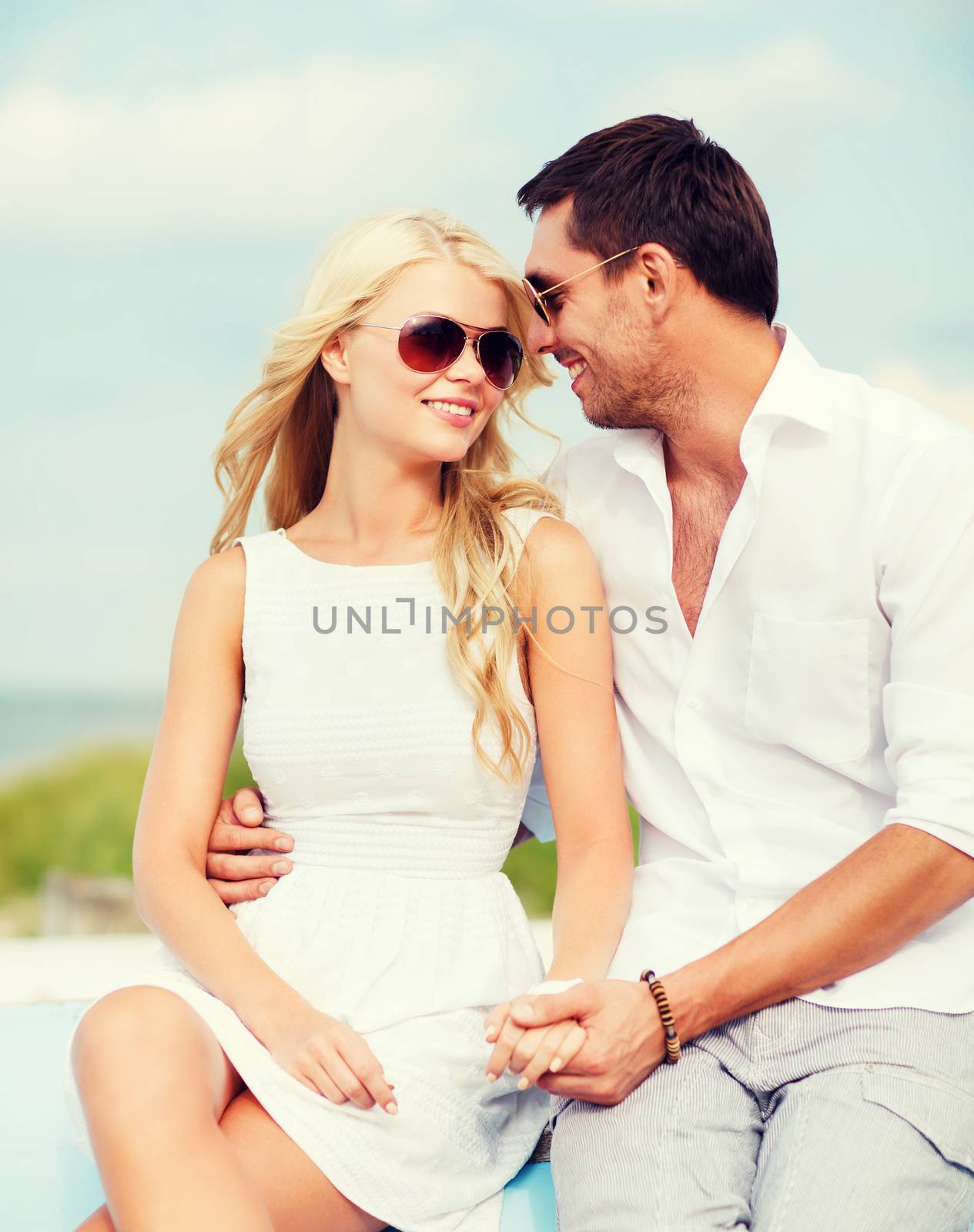 summer holidays and dating concept - couple in shades at seaside